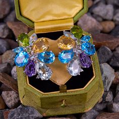 This fun and colorful pair of earrings are each accented with three (3) natural blue topaz, one (1) natural aquamarine, two (2) natural peridot, one (1) natural citrine, one (1) natural amethyst, one (1) natural prasiolite, and five (5) diamonds all set into prong settings. The earrings measure 32.3mm X 24.6mm and are finished with posts and 14k white gold friction backs. Elegant Multi-stone Topaz Gemstones, Fine Jewelry Topaz Earrings With Gemstone Accents, Anniversary Blue Topaz Multi-stone Earrings, Anniversary Multi-stone Blue Topaz Earrings, Multi-stone Topaz Gemstones As Gift, Multi-stone Blue Topaz Earrings As Gift, Natural Citrine, Natural Aquamarine, One 1