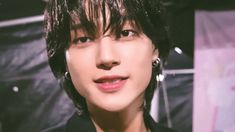 a close up of a person wearing earrings and a black shirt with white writing on it