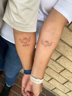 two people holding hands with tattoos on their arms