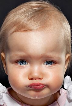 a baby girl with blue eyes and blonde hair