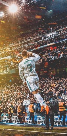 a soccer player is jumping in the air at a game while fans watch from the stands