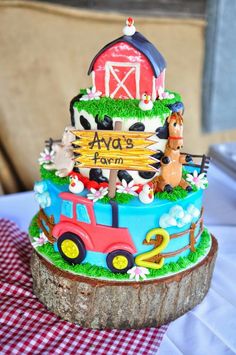 a cake with farm animals on it sitting on top of a wooden tablecloth covered table