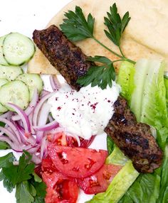 a plate filled with meat, vegetables and pita bread