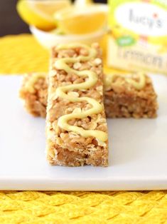 two pieces of granola bars sitting on top of a white plate with lemons in the background