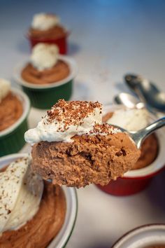 a spoon with some kind of dessert on it in front of other cupcakes