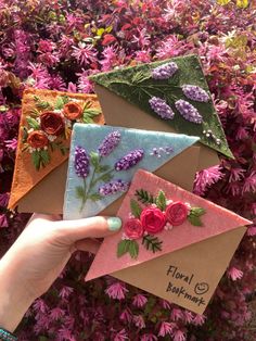 hand holding four different colored envelopes with flowers on them