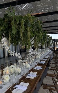 a long table is set with white flowers and greenery