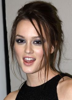 a close up of a person wearing a black dress and blue eyeshadow with her hair in a pony tail