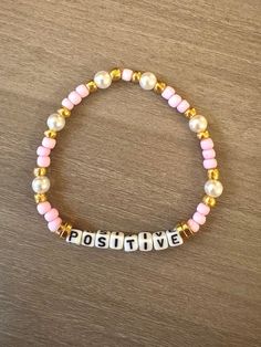 a bracelet with the word poshy written on it and two pearls attached to it