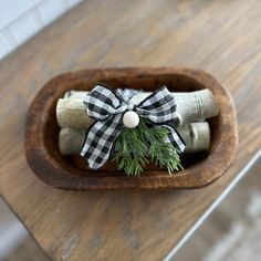 a wooden bowl filled with rolled up cinnamons and wrapped in black and white ribbon