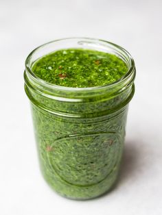 a jar filled with green pesto sitting on top of a table