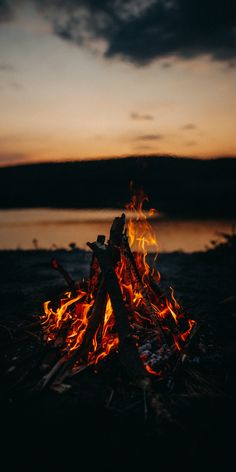 a campfire is lit at night with the sky in the background