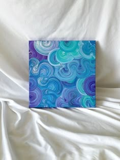 a blue and purple painting on a white sheet with watercolor swirls in the background