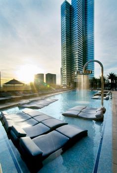 an outdoor swimming pool with lounge chairs and buildings in the background