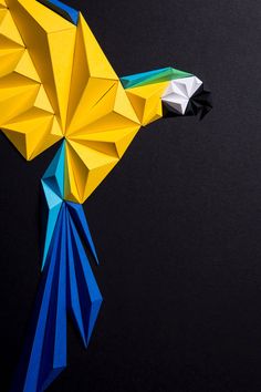 an origami bird made out of paper on a black background with the colors of blue, yellow and green