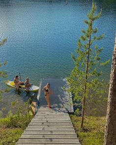 two people on surfboards are at the end of a dock with a paddle boat