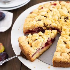 a piece of pie on a plate with a slice missing from it and some fruit nearby