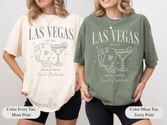 two women wearing t - shirts with las vegas and cocktails designs on the front