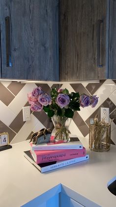 three books are stacked on top of each other in front of a vase with roses