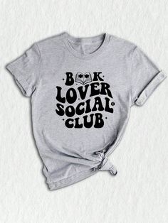 Introducing our exclusive Social Club Bookish T-Shirt, a must-have for all bookworms and avid readers! ✨ Perfect for book club enthusiasts and lovers of literature, this unique design merges style and intellect to create a statement piece for any occasion. Our social club shirt features a captivating illustration that brings together various elements of the bookish world.  The center focuses on a charming library, adorned with piles of books and a cozy reading chair. Surrounding it, adorable emojis depict the joy of reading, expressing your love for books without saying a word! ❤️ For those who are passionate about banned books or appreciate literary rebellions, this shirt showcases a subtle nod with a red "BANNED" stamp, adding an extra edge to your wardrobe.  Designed with comfort in min Cozy Reading Chair, Book Club Shirt, Bookworm Shirt, Librarian Shirt, Reading Gifts, Reading Shirts, Reading Chair, Banned Books, Book Fair