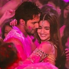 a man and woman hugging in front of a crowd at a party with pink powder all over them