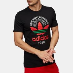 a man in black adidas t - shirt and red shorts standing with his hand on his hip