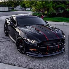 a black mustang with red stripes parked on the street