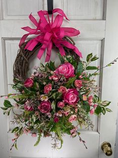 a wreath with pink flowers hanging on a door