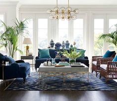 a living room filled with lots of furniture and plants on top of a wooden floor