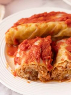 a white plate topped with lasagna covered in sauce