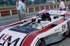 the race car is parked on the side of the road with two men looking at it