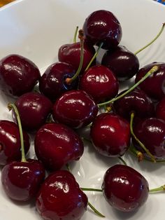 a white bowl filled with cherries on top of a table