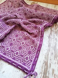 a purple crocheted blanket laying on top of a wooden floor