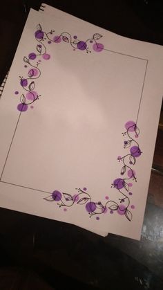 a piece of paper with purple flowers and vines on it, sitting on top of a table