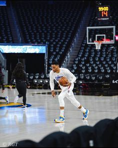 a man holding a basketball on top of a hard surface court in front of a crowd