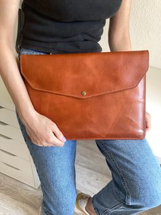 a woman holding a brown leather clutch bag