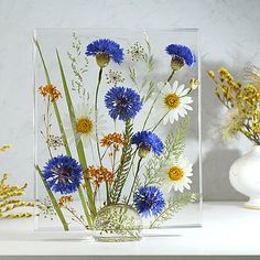 a vase filled with blue and white flowers on top of a table next to another vase