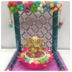 an elephant figurine sitting on top of a purple chair with flowers around it