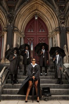 a group of people standing on steps with umbrellas in front of a church door