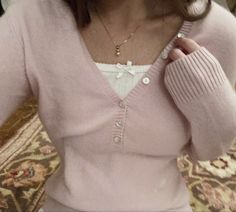 a woman is wearing a pink sweater and holding a cell phone