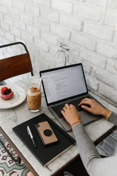 a person sitting at a table with a laptop and cup of coffee in front of them