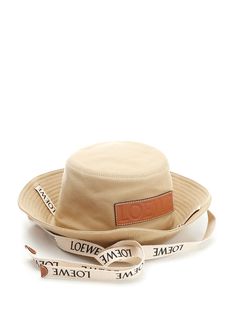 Beige cotton bucket hat from Loewe Paula' s Ibiza with logo ribbon and calfskin patch embossed Anagram calfskin patch. Designer Adjustable Bucket Hat With Curved Brim, Luxury Beige Hat With Embroidered Logo, Luxury Wide Brim Summer Bucket Hat, Luxury Wide Brim Bucket Hat For Summer, Luxury Hats With Logo Patch And Curved Brim, Loewe Paula's Ibiza, Cotton Bucket Hat, Versace Designer, Hat For Women