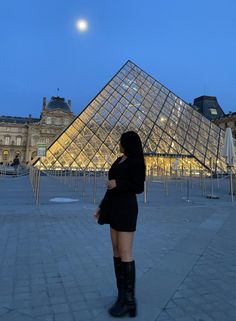 a woman standing in front of the pyramid at night with her back turned to the camera