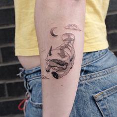 a person with a tattoo on their arm that has a drawing of a cat in the sky