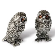 two silver owl figurines sitting next to each other on top of a white surface