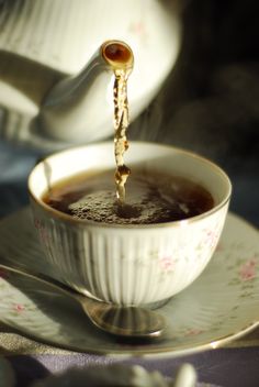 tea being poured into a white cup on a saucer