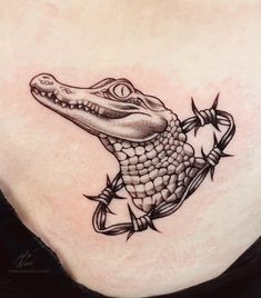 an alligator tattoo on the back of a woman's stomach, with barbed wire around it