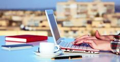 a woman is typing on her laptop at the table with a cup of coffee in front of her