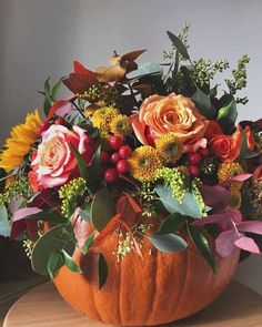 a pumpkin filled with lots of flowers on top of a table