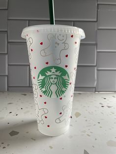 a starbucks cup with a green straw in it on a table next to a tiled wall